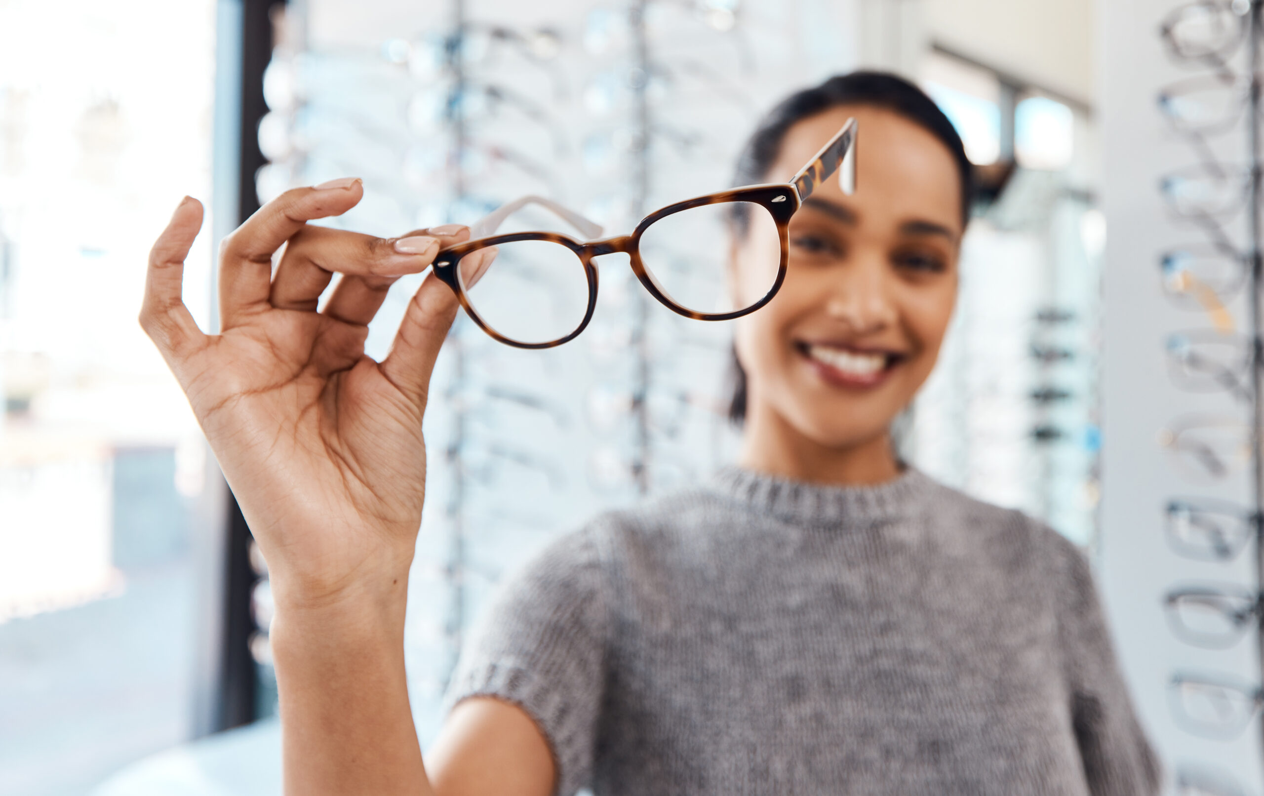 Raise your glasses to good eye health. Shot of a young woman buying a new pair of glasses at an optometrist store.